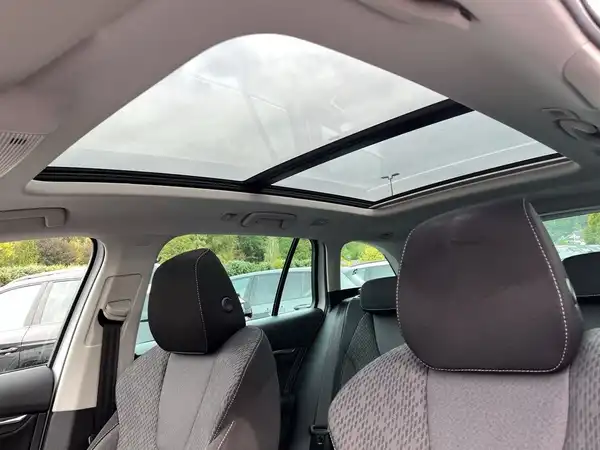Innenaufnahme des Fahrzeugs mit grauen, gemusterten Sitzen und einem Panoramadach.