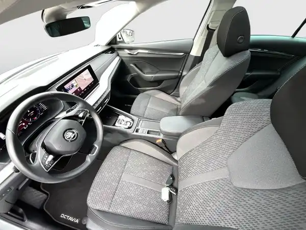 Das Bild zeigt die Inneneinrichtung eines ŠKODA OCTAVIA, mit schwarzen und grauen Sitzen und einem modernen Armaturenbrett.