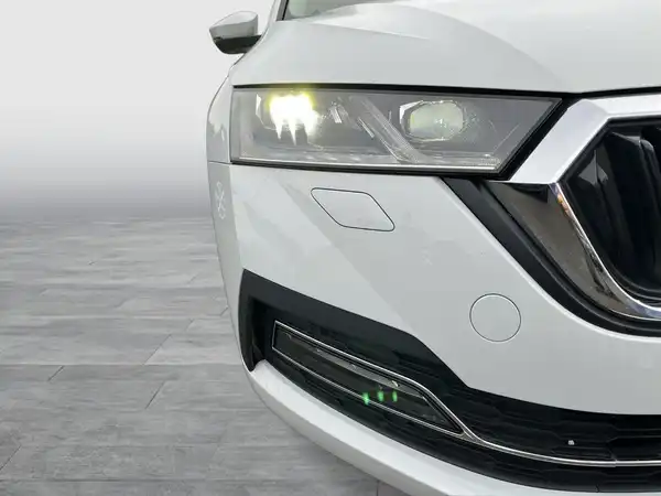 Das Bild zeigt die Vorderansicht eines weißen ŠKODA OCTAVIA mit Fokus auf die Scheinwerfer und das Kühlergrill.
