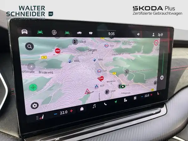 Das Bild zeigt den Innenraum eines ŠKODA OCTAVIA RS mit einem Navigationsdisplay, das eine Kartenansicht darstellt. Das Interieur ist schwarz und das Händlerslogo ist sichtbar.