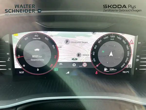 Eine Innenaufnahme des Fahrzeugs, die das Armaturenbrett mit einem Infotainment-System zeigt. Die Interieurfarbe ist schwarz. Das Händlerlogo ist sichtbar und es gibt markante Texteinblendungen.