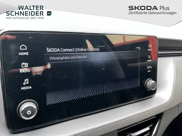Das Bild zeigt das Innenleben eines ŠKODA Fahrzeugs, genauer gesagt das Display des Infotainmentsystems. Es ist eine Innenaufnahme in schwarzer Farbe, und es ist das Händlerlogo von Walter Schneider eingeblendet.