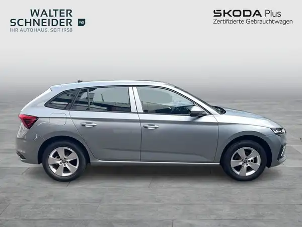 Seitenansicht eines silbernen ŠKODA Scala, mit Händlerlogo und Werbetext im Bild.