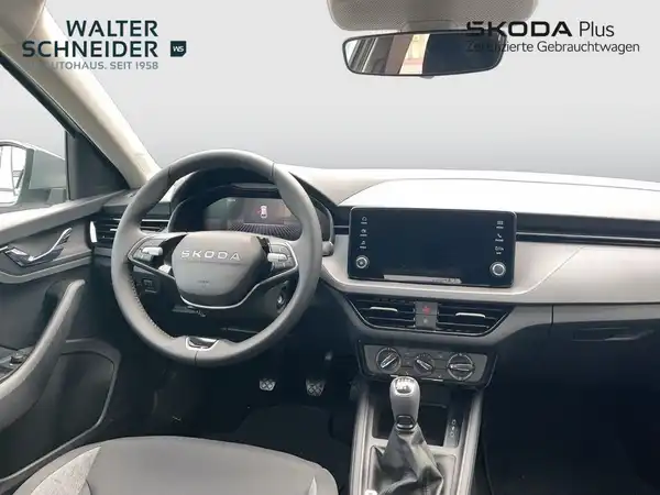Das Bild zeigt den Innenraum eines ŠKODA SCALA mit einem schwarzen und grauen Interieur aus Stoff und Kunstleder. Das Händlerinformationslogo "WALTER SCHNEIDER" ist sichtbar.