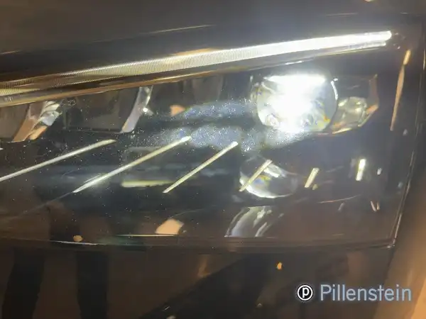 Nahaufnahme des Scheinwerfers eines schwarzen ŠKODA SCALA, mit dem Händlerlogo. Es zeigt Details der Beleuchtung.