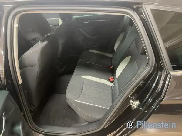 Das Bild zeigt die Rückbank des Fahrzeugs, eine Innenaufnahme in Schwarz mit dunklem Interieur und hellen Akzenten, aufgenommen aus einem Blickwinkel von innen.