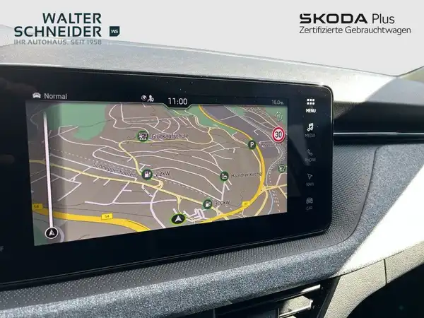 Das Bild zeigt eine Innenansicht des ŠKODA Fahrzeug mit einem Navigationsgerät, das eine Kartenansicht anzeigt. Das Interieur ist schwarz. Das Händlerlogo ist sichtbar und es gibt markante Texteinblendungen.