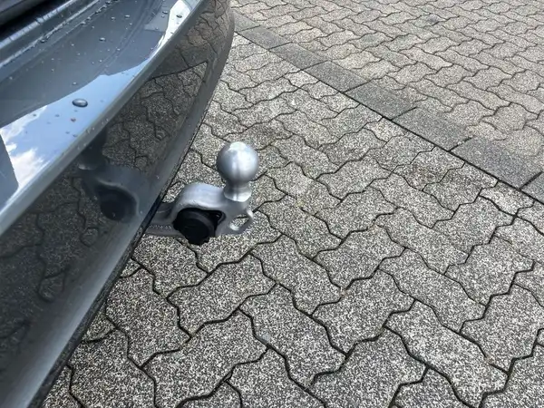 Das Bild zeigt die Rückansicht eines grauen Fahrzeugs, das mit einer Anhängerkupplung ausgestattet ist.