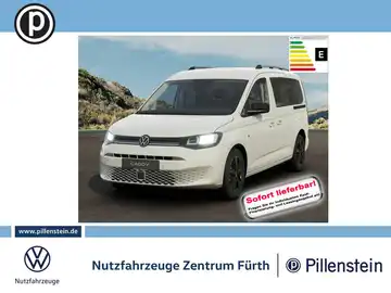 Das Bild zeigt einen weißen VW Caddy aus der Frontansicht, mit dem Händlerlogo und markanten Texteinblendungen. Es wird angezeigt, dass das Fahrzeug sofort lieferbar ist.