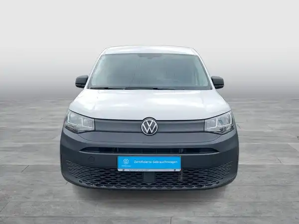 Das Bild zeigt einen weißen VW Caddy von vorne. Es enthält eine markante Texteinblendung.