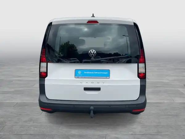 Das Bild zeigt die Rückansicht eines weißen VW Caddy. Es ist ein Fahrzeugbild, aufgenommen von hinten, und enthält ein Händlerlogo sowie markante Texteinblendungen.