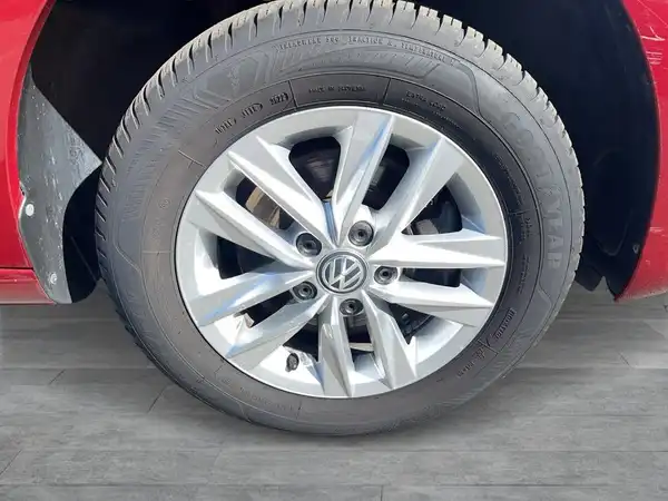 Das Bild zeigt die Felge eines roten Volkswagen Fahrzeugs, aufgenommen von der Seite.