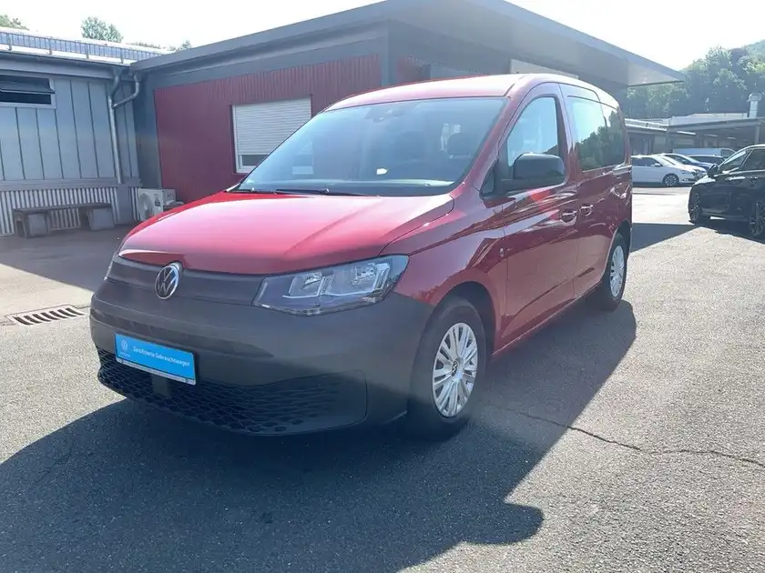 Das Bild zeigt einen roten VW Caddy von der Seite. Es sind Händlerlogo und Texteinblendungen zu sehen.