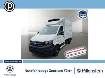 Das Bild zeigt einen weißen VW Crafter von vorne. Im Hintergrund sind Händlerlogos und der Hinweis 'Sofort lieferbar' zu sehen.