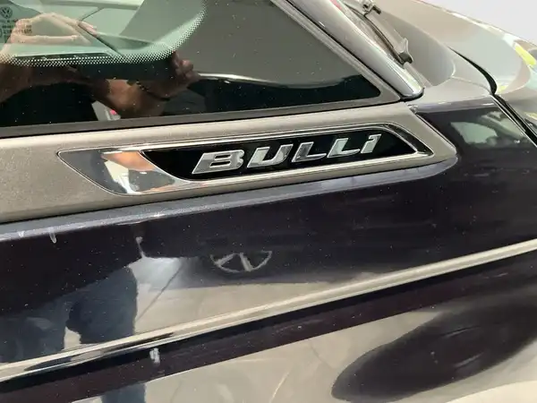 Das Bild zeigt die seitliche Ansicht eines schwarzen VW Multivan mit dem Schriftzug 'BULLI' an der Seite. Es handelt sich um ein Fahrzeugbild, ohne Händlerlogo, aber mit markanten Texteinblendungen.