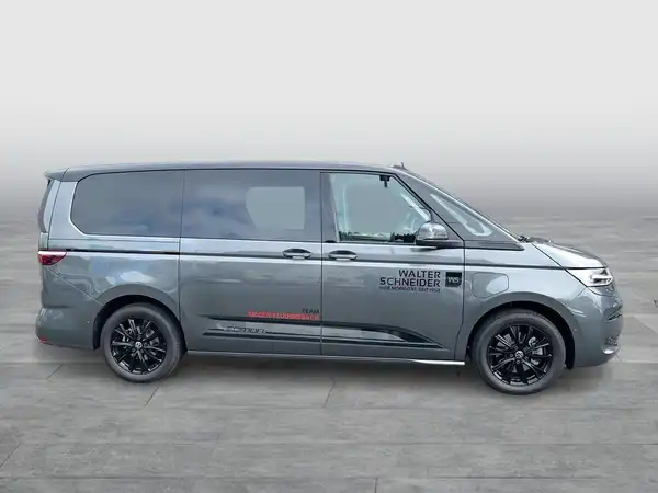 Das Bild zeigt einen grauen VW Multivan von der Seite. Es sind markante Texteinblendungen vom Händler zu sehen.