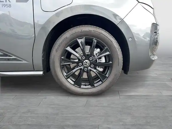 Das Bild zeigt die Seite eines grauen VW Multivan mit einem Blick auf das Rad und die Felge.