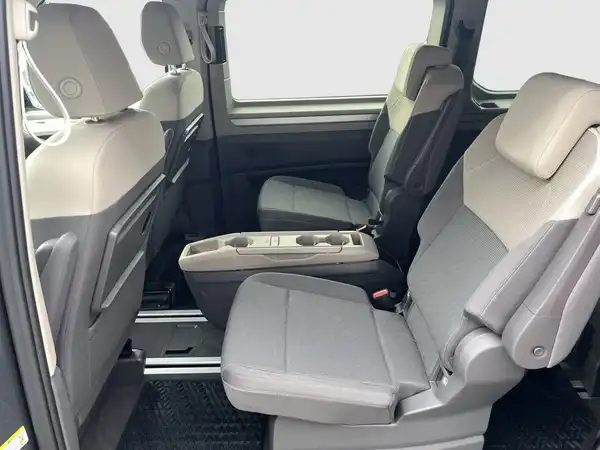 Das Bild zeigt den Innenraum eines VW Multivan mit zwei vorderen Sitzen in schwarz-grau.