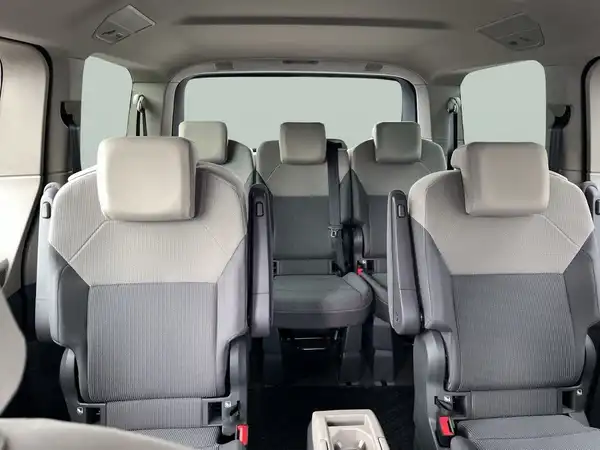 Innenaufnahme des Fahrzeugs VW Multivan mit grauen Sitzen und einem modernen Interieur.
