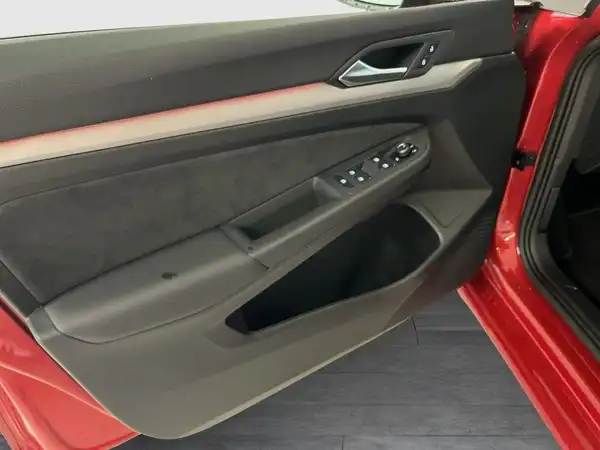 Das Bild zeigt die Innenansicht der Fahrertür eines roten Fahrzeugs mit schwarzem Interieur und roten Akzenten.