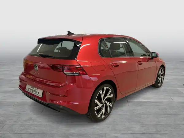 Das Bild zeigt einen roten VW Golf von hinten, mit markanten Texteinblendungen.