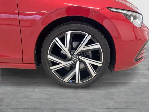 Das Bild zeigt die Seite eines roten VW Golf mit einem Fokus auf dem Rad und einem Teil des Wagens.