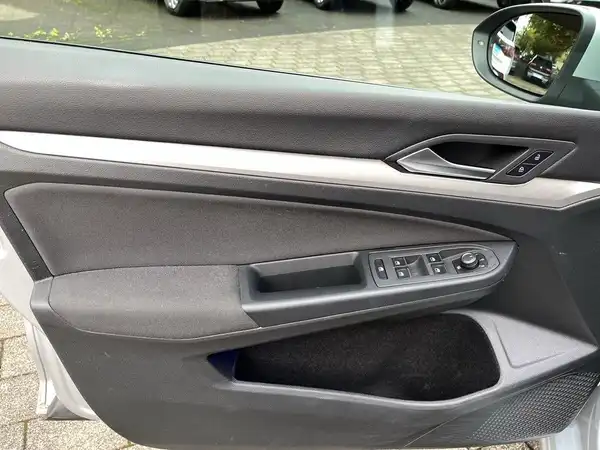 Innenaufnahme des Fahrzeugs, zeigt die Türverkleidung mit Knöpfen und einem Spiegel.