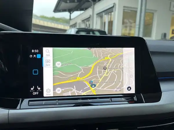 Das Bild zeigt eine Innenaufnahme des Fahrzeugs mit einem Navigationsgerät, das eine Karte anzeigt.