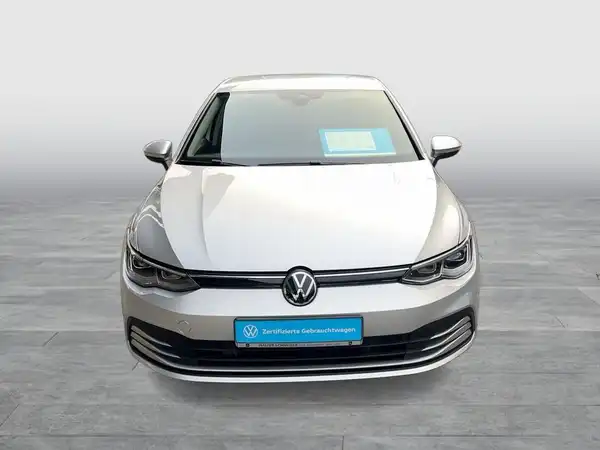 Das Bild zeigt einen silbernen VW Golf, aufgenommen von vorne. Im Bild ist das Händlerlogo sichtbar und es enthält markante Texteinblendungen.