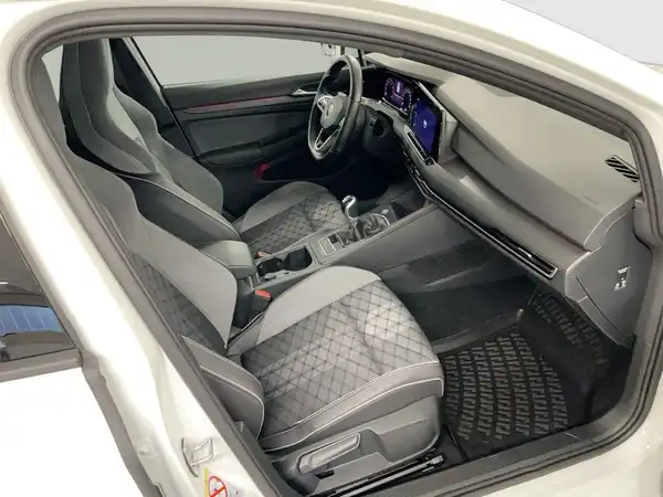 Das Bild zeigt das Innenraum eines weißen VW Golf mit grauen Sitzen und Karomuster.