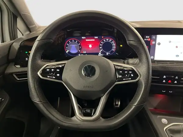 Das Bild zeigt das Inneninterieur eines VW Golf mit einem schwarzen Lenkrad und einem digitalen Display.