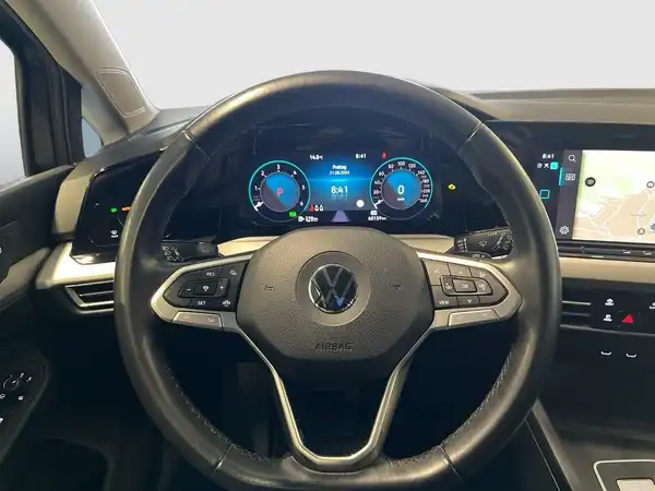 Das Bild zeigt das Innere eines VW Golf Variant mit schwarzem Interieur und einer Übersicht über das Armaturenbrett und das Steuer.