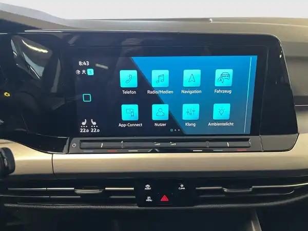 Das Bild zeigt das Innere eines Fahrzeugs mit einem schwarzen Interieur und einem Bildschirm, der verschiedene Funktionen anzeigt.