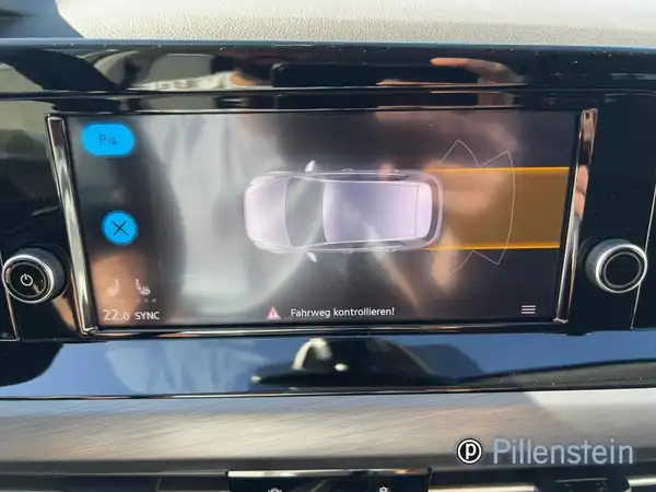 Das Bild zeigt das Innenraumdisplay eines VW GOLF mit einer Rückfahrkameraansicht. Der Innenraum scheint in schwarzer Farbe gehalten zu sein. Es sind einige markante Texteinblendungen zu sehen, und ein Händlerlogo ist sichtbar.
