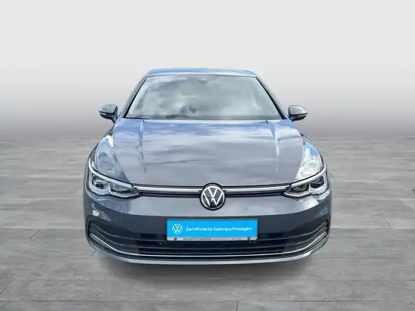 Ein grauer VW Golf, aufgenommen von vorne mit einem Händlerlogo und markanter Texteinblendung.