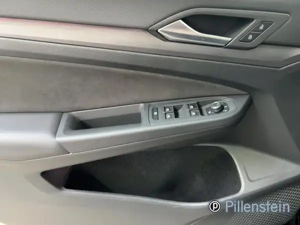 Das Bild zeigt die Innenansicht der Fahrertür eines Volkswagen Golf, die in schwarzer Farbe gehalten ist, mit Bedienelementen für die Fensterheber und einem Händlerlogo.