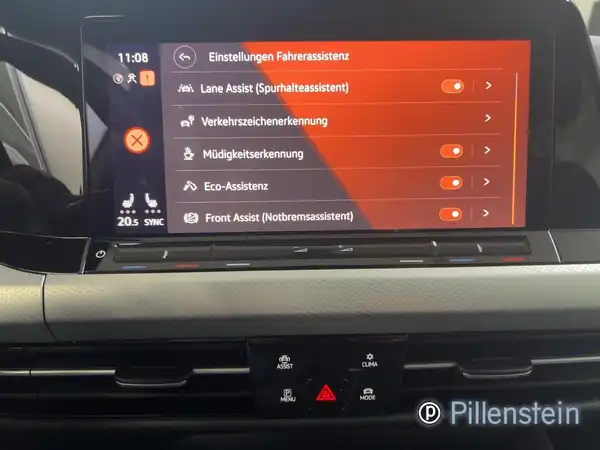 Das Bild zeigt das Innere eines VW Golf Variant mit einem Bildschirm, der Einstellungen für Fahrassistenzsysteme anzeigt. Der Innenraum ist schwarz und das Händlerinformationen sind sichtbar.