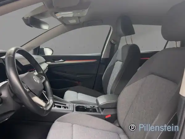 Innenaufnahme eines VW Golf Variant in schwarzem Interieur mit grauen Akzenten, Händlerlogo sichtbar.