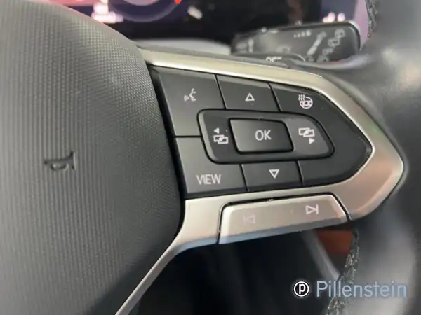 Das Bild zeigt das Lenkrad und Bedienelemente im Innenraum eines VW Golf Variant. Das Interieur ist schwarz und das Händlerlogo ist sichtbar.