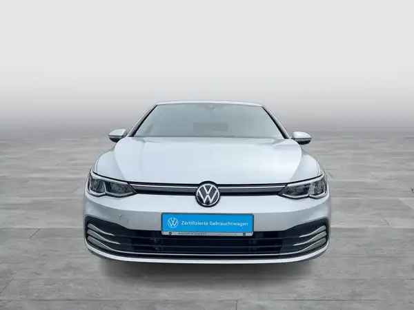 Das Bild zeigt einen silbernen VW Golf aus der Frontalansicht. Im Bild ist das Händlerlogo integriert und es gibt markante Texteinblendungen.