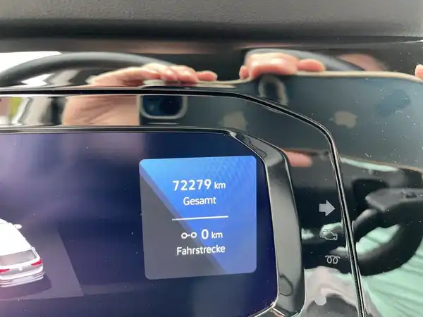 Das Bild zeigt eine Innenaufnahme des Fahrzeugs, insbesondere das Display, das Kilometerstand und Fahrstrecke anzeigt. Das Interieur ist schwarz.