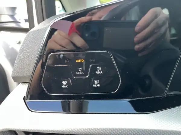 Das Bild zeigt eine Innenaufnahme des Fahrzeugs mit einem schwarzen Interieur. Es enthält markante Texteinblendungen auf den Bedienelementen.