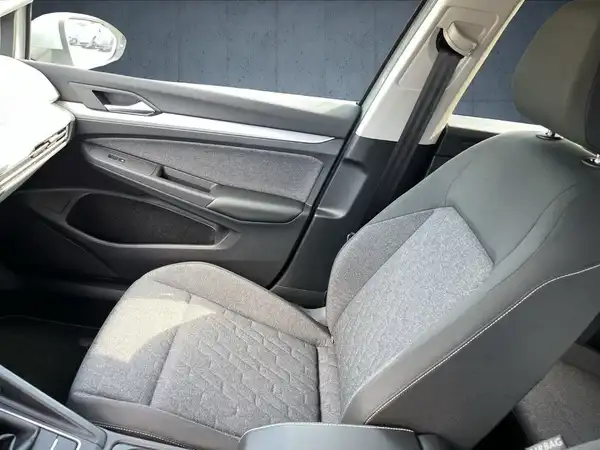 Das Bild zeigt den Innenraum eines Fahrzeugs, insbesondere den Fahrersitz mit einer grauen Polsterung und strukturiertem Muster.