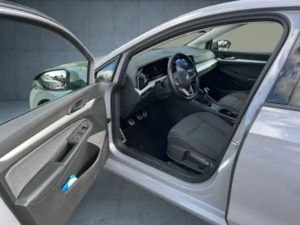 Das Bild zeigt den Innenraum eines grauen Fahrzeugs mit schwarzem Interieur. Die Aufnahme ist von der offenen Fahrertür aus gemacht.