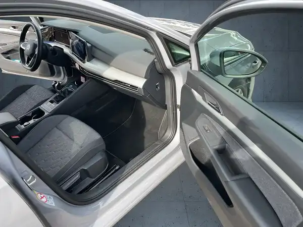 Das Bild zeigt den Innenraum eines silbernen Fahrzeugs, aufgenommen von der Seite mit geöffneter Tür. Der Innenraum ist in schwarz gehalten.