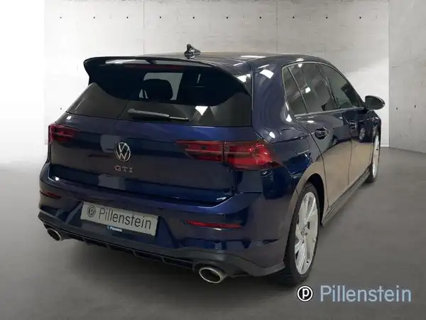 Das Bild zeigt einen blauen VW Golf GTI von hinten. Auf dem Foto ist das Händlerlogo 'Pillenstein' zu sehen.