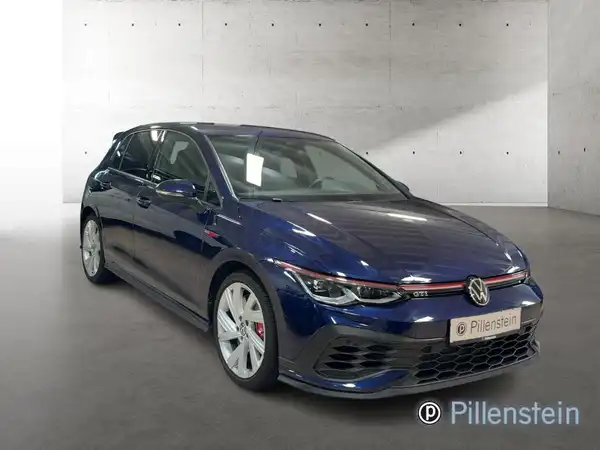 Das Bild zeigt einen blauen VW Golf GTI von der Seite, aufgenommen in einem Studio mit einem sichtbaren Händlerlogo von Pillenstein.