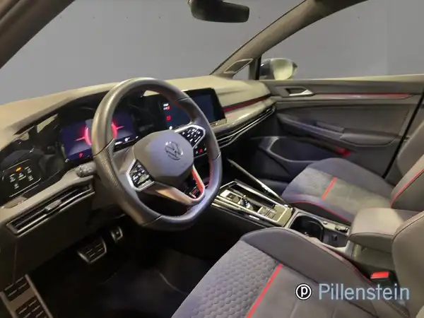 Innenaufnahme eines VW Golf GTI mit schwarzem Interieur und roten Akzenten, Händlerlogo im Bild.