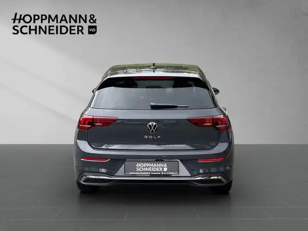 Das Bild zeigt einen grauen VW Golf von hinten. Im Hintergrund ist ein Händlerlogo zu sehen.