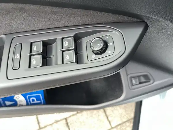 Das Bild zeigt das Innenleben des Fahrzeugs, insbesondere die Bedienelemente an der Fahrertür in schwarzer Farbe.